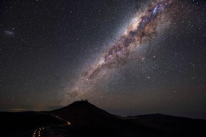 El Cerro Paranal, de 2600 metros de altura, se recorta contra un cielo oscuro con el majestuoso arco de la Vía Láctea, lo que demuestra las excelentes condiciones de observación en Paranal, que disfruta de unas 300 noches despejadas al año. Estas condiciones de observación fueron un factor clave en la decisión de construir en ese sitio el Very Large Telescope (VLT) de ESO, que se puede distinguir en esta imagen en la cima de la montaña. El VLT es el instrumento óptico más avanzado del mundo y una herramienta invaluable que ayuda a los astrónomos a estudiar el Universo y a comprenderlo mejor. Crédito de la imagen: A. Ghizzi Panizza/ESO
